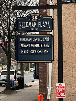 The image shows a sign for  Beckman Plaza  with additional information about dental care services provided by Bryant Munn, including a note about hair expressions.