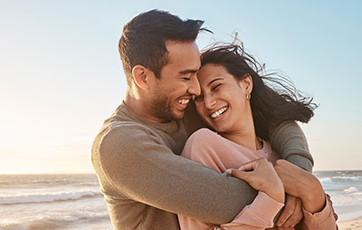 A man and woman embracing on a beach at sunset.