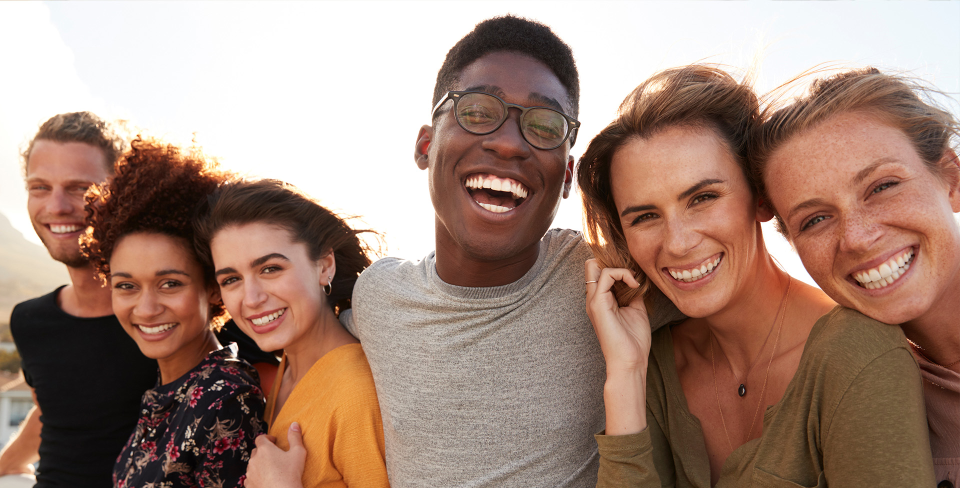 The image shows a group of five smiling individuals posing together for a photograph with a joyful atmosphere, likely during a social gathering or event.