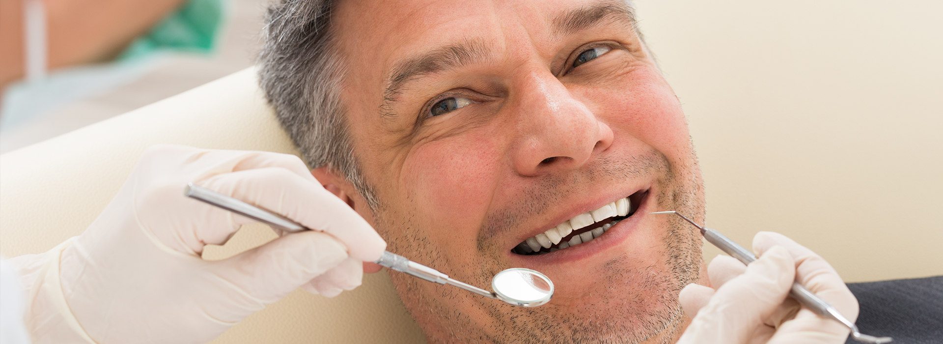 A man receiving dental treatment with a smiling expression while seated in a dental chair.