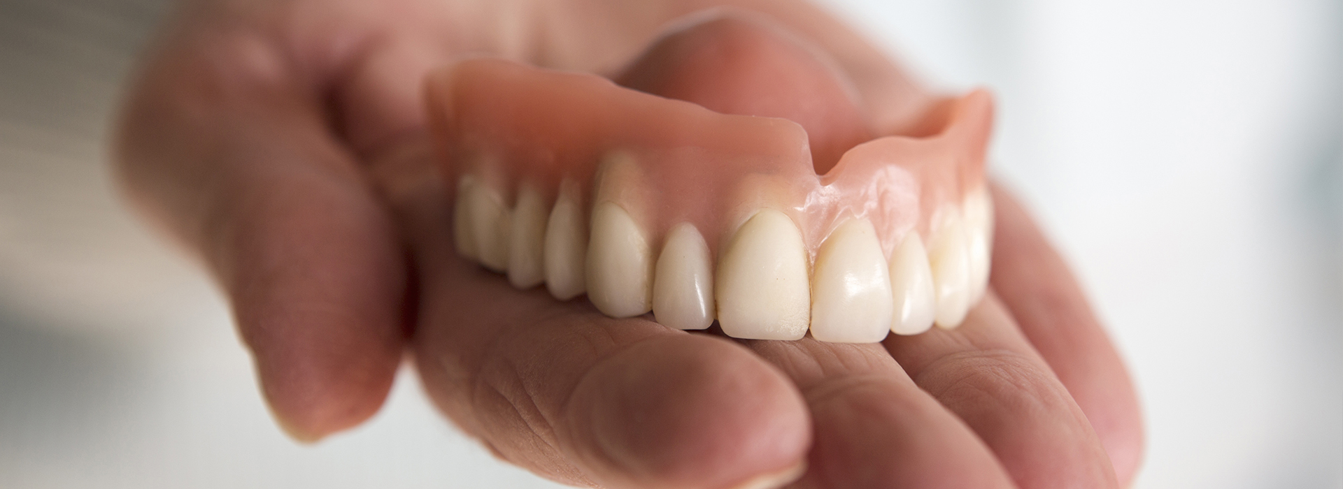 A hand holding an artificial human mouth with teeth.