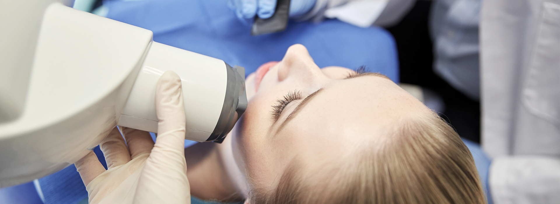 A person receiving dental treatment with a dentist using a magnifying loupe.