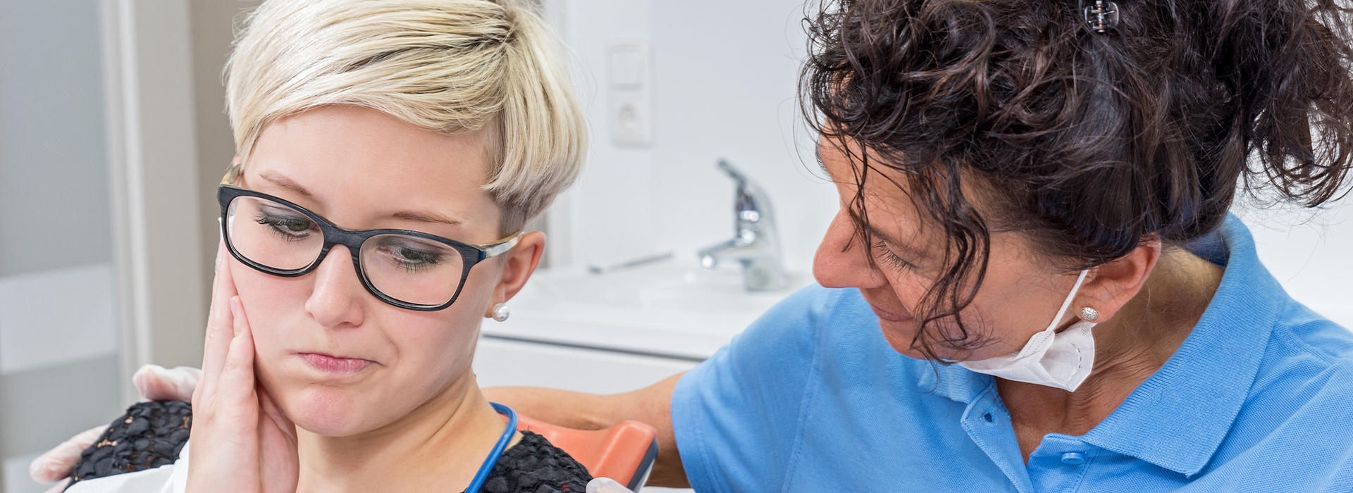 The image shows two individuals engaged in a dental care session, with one person receiving care from another who appears to be a professional in the field of dentistry.