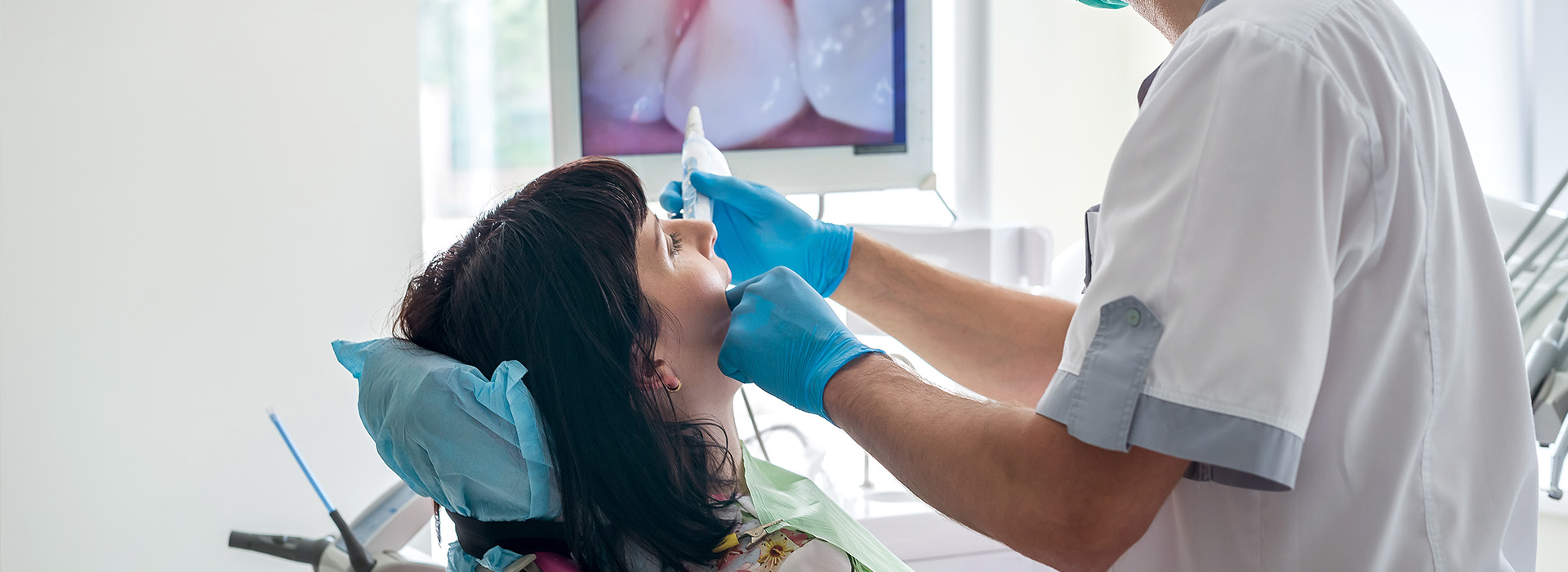 A dental professional performing a procedure on a patient s mouth while wearing protective gloves and equipment.