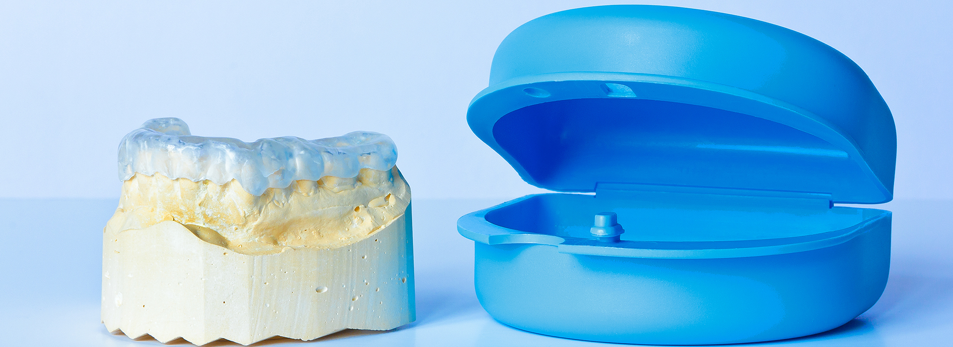 The image shows a blue toothbrush next to a yellow dental implant model.