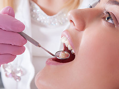 The image features a close-up of a person receiving dental care from a professional, with a focus on the dental tools being used.