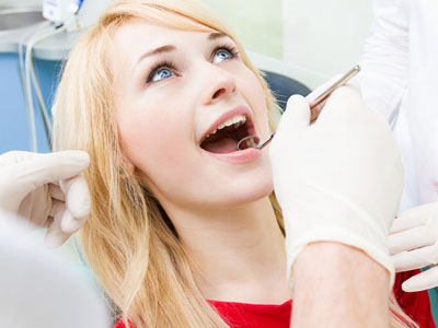 A woman receiving dental care with a dentist performing a procedure.